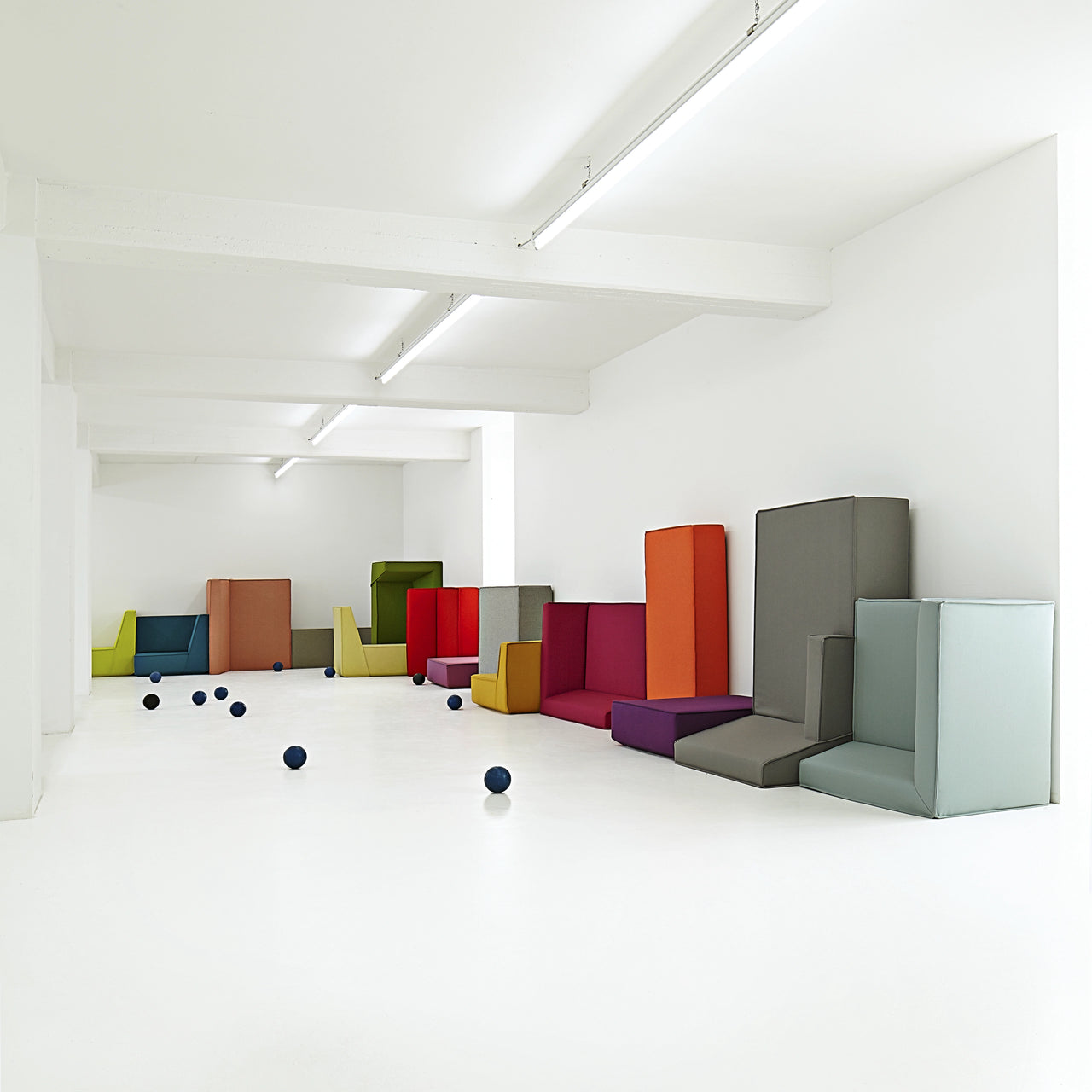 Mehrteiliges modulares Sofa in kräftigen Farben, frei arrangiert in einem weißen Raum