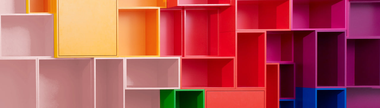 Cubit Regalwand aus farbigen Modulen in Rot-, Rosa- und Gelbtönen, dynamisch angeordnet für ein lebendiges Raumdesign