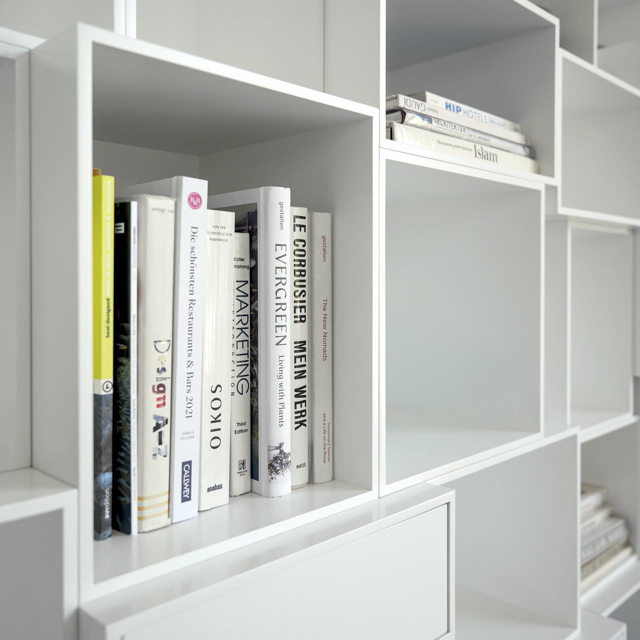 Nahaufnahme eines weißen Regalsystems mit vertikal und horizontal angeordneten Büchern