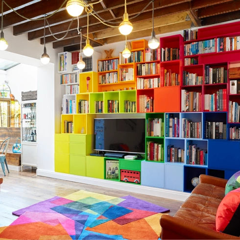 Regalwand in bunten Farben mit integriertem TV, kombiniert mit Büchern und Deko.