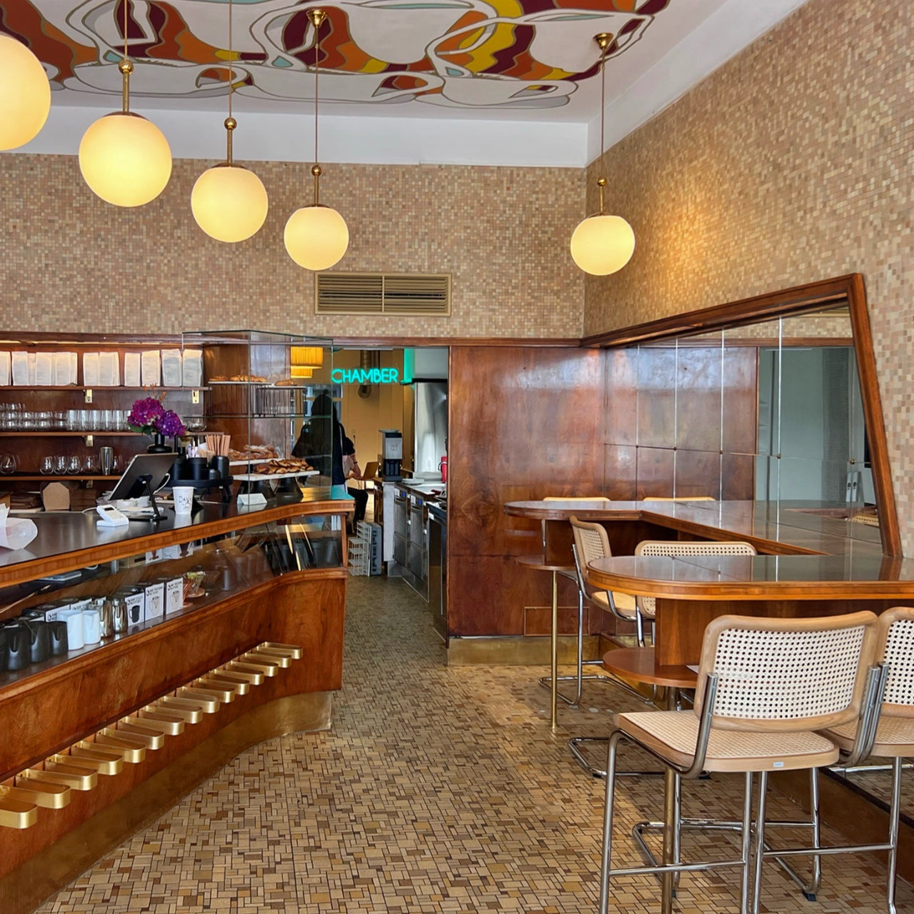 View from the entrance area of a Viennese café with a round counter and stool seating in the direction of Chamber Wien.