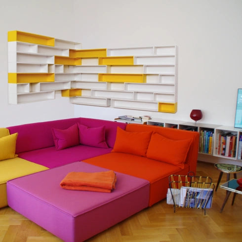CD Regal in Weiß und Gelb, minimalistisch gestaltet, kombiniert mit bunten Sofas.