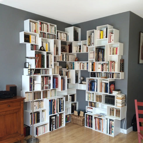 Weißes Eckregal, ideal für Bücher, kombiniert mit einer grauen Wand und Holzboden.