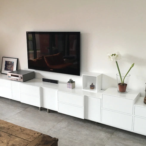 Weißes Hifi Regal mit Schubladen, kombiniert mit einem Fernseher und Deko.