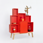 Modulares Regalsystem in Rot mit unterschiedlich großen Fächern und Dekoobjekten auf Holzgestell