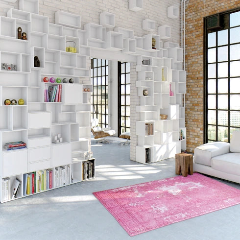 Weißes Regalsystem in einem Loft, kombiniert mit Backsteinwänden und großen Fenstern.