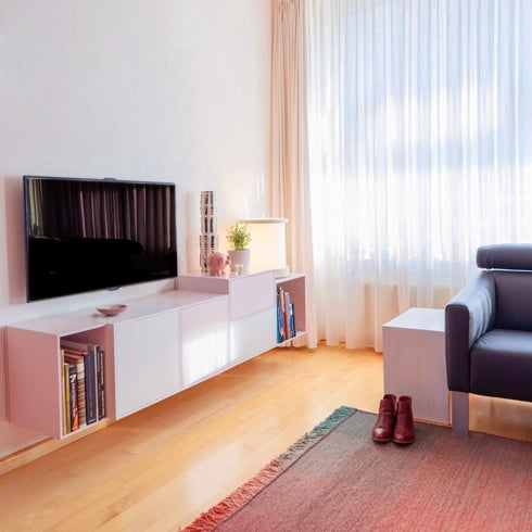 Weißes TV Regal, kombiniert mit einem Flachbildfernseher, hellem Boden und gemütlicher Einrichtung.