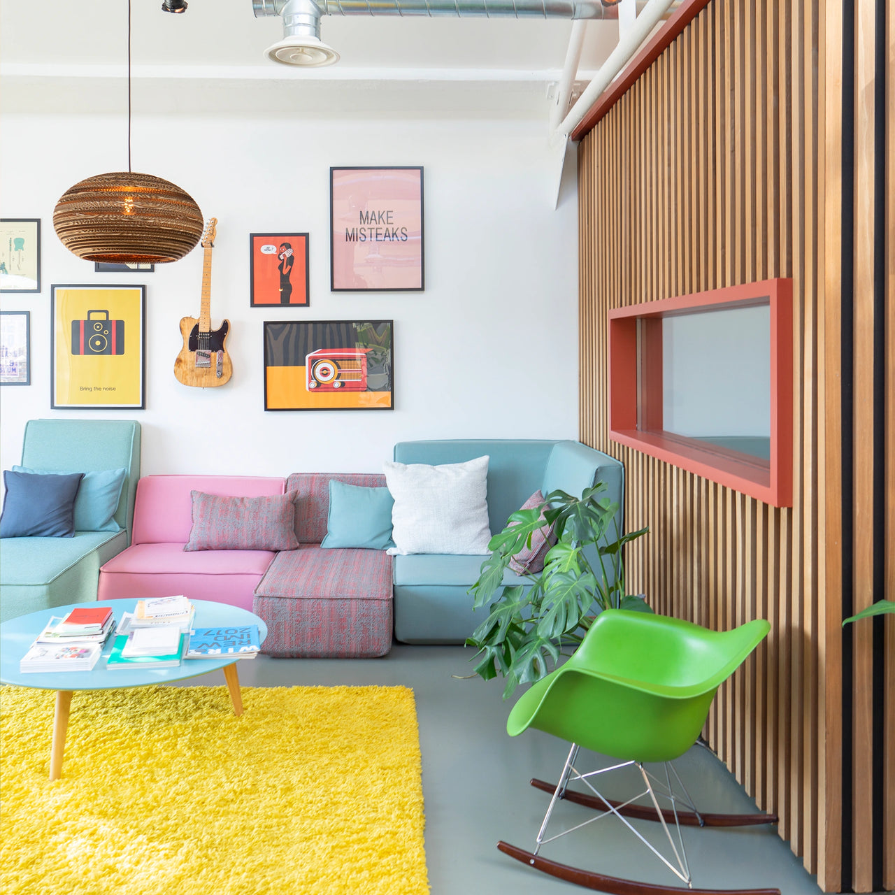 Bright room with colorful sofa modules, yellow carpet, green rocking chair and decorative picture wall - taken in the Cubit Lookroom Paris