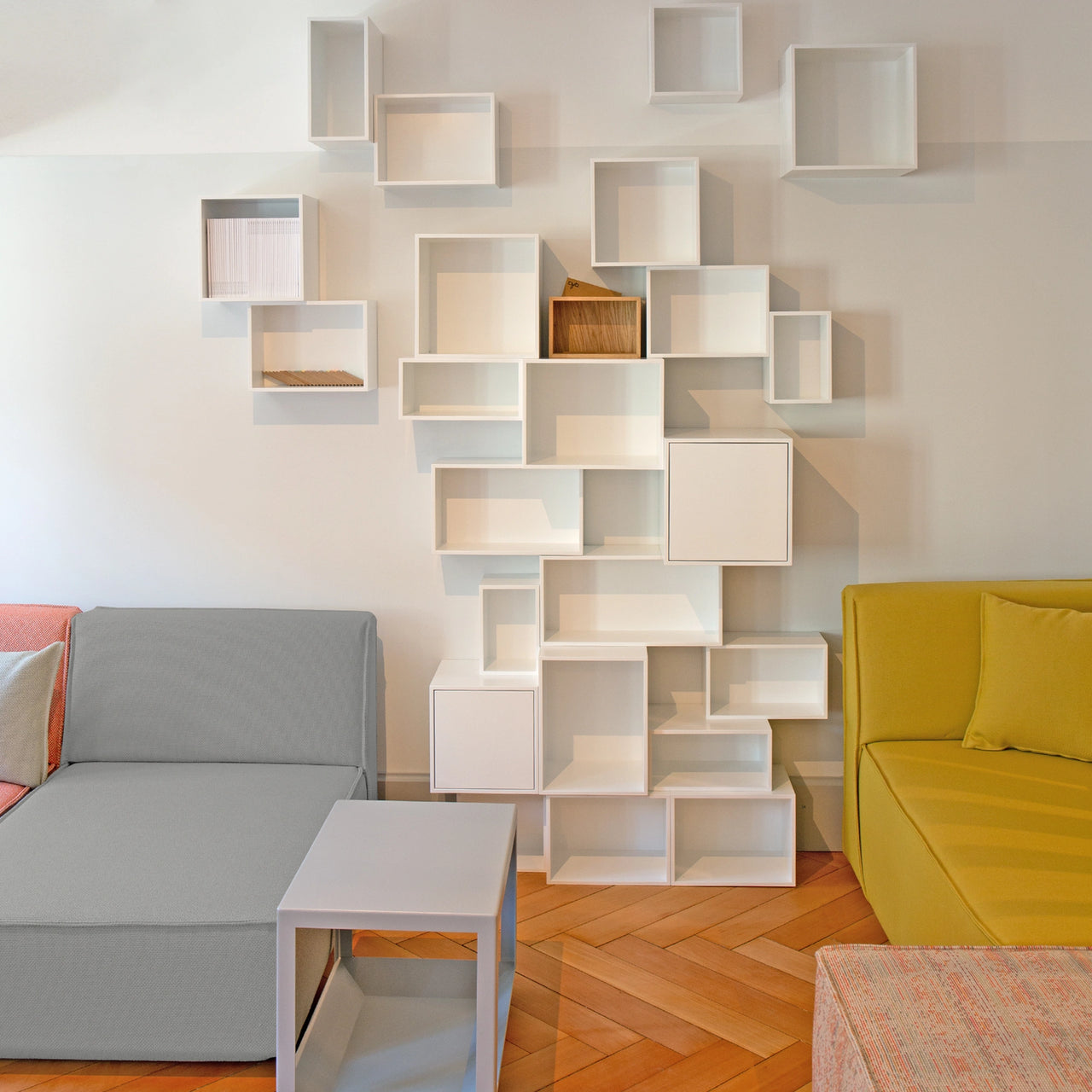 Modular Cubit Shelving in white as a wall installation in the Zurich Lookroom, combined with colored sofa modules and a small side table