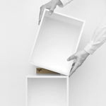 Two hands position a white Cubit shelf module on top of another - minimalist scene with logo