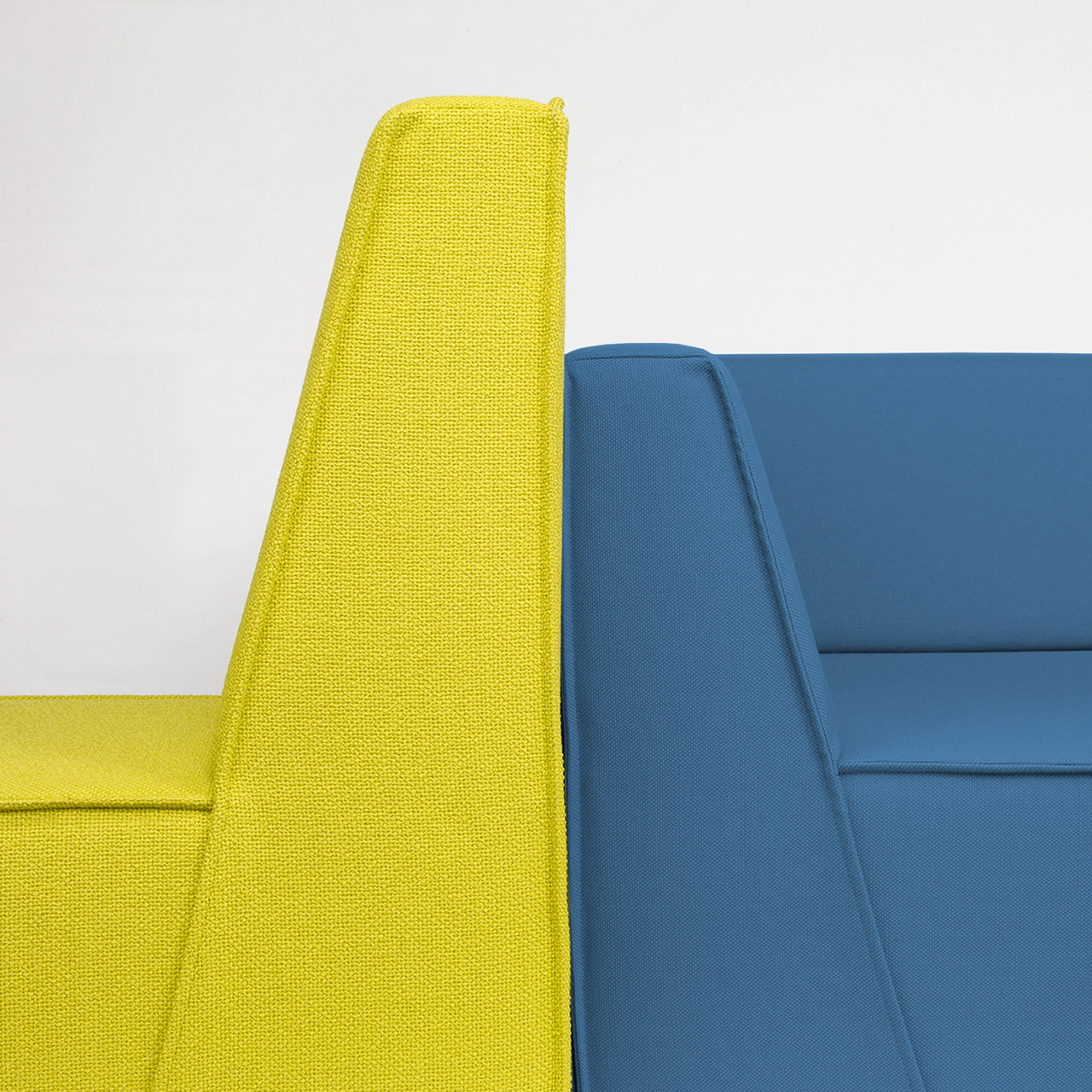 Close-up of two Cubit sofa modules in bold yellow and blue in the Delbrück showroom, back view emphasizes the design language and fabric structure