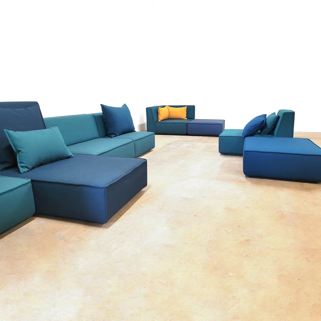 Overview of the showroom in Delbrück with modular Cubit sofas in various shades of blue and color-coordinated cushions, presented on a light floor.