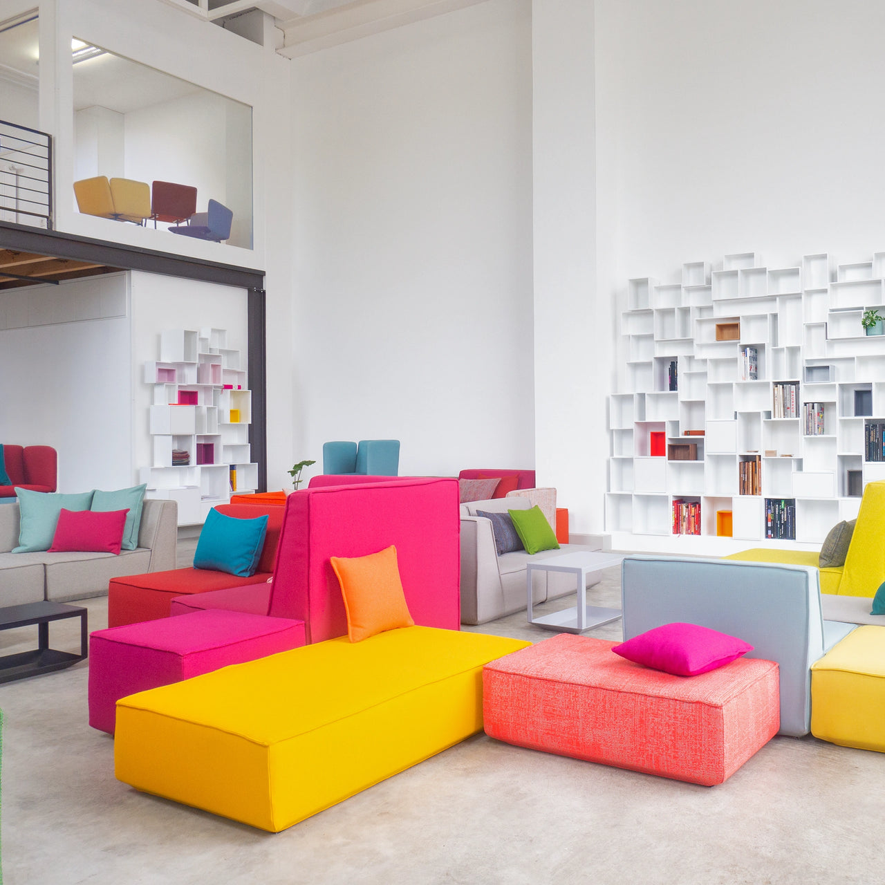 Bright showroom in Düsseldorf with colorful modular Cubit sofas and white shelving modules on the walls, presented in a spacious loft atmosphere