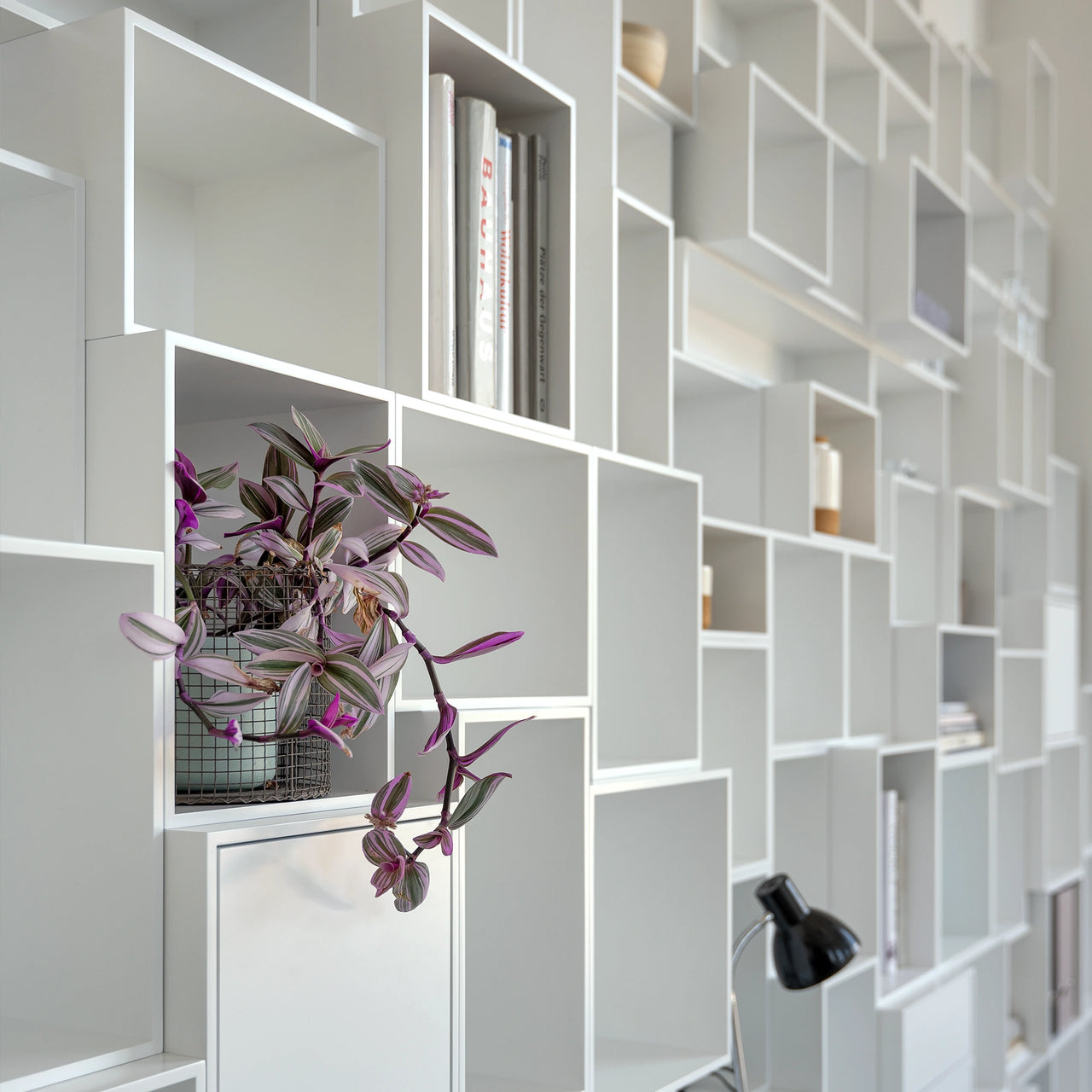 Detailed view of a white, modular Cubit shelving wall in the Düsseldorf showroom with integrated plant, books and accessories