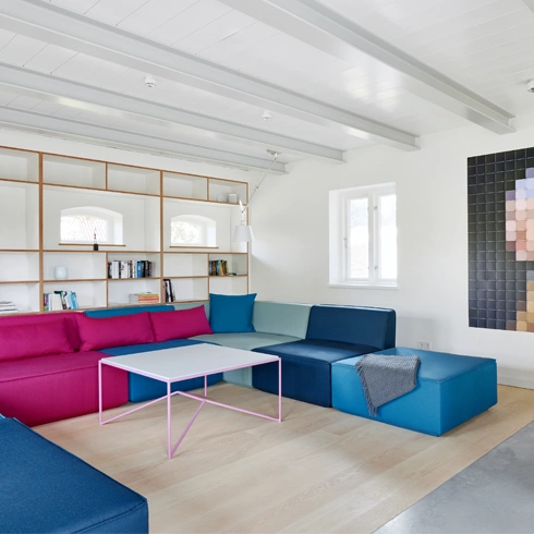 Corner sofa in blue and pink, combined with light wooden furniture and modern interior design.