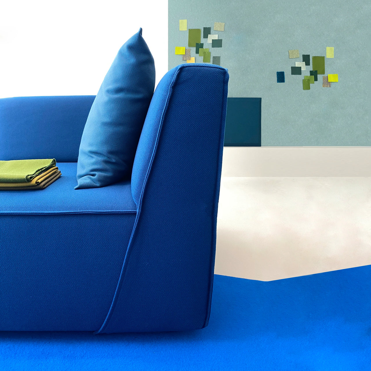 Side view of a blue sofa with fabric patterns - in the background wall with collage as a color study