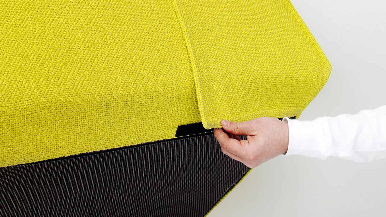 Close-up of a hand removing the removable fabric cover of a Cubit Sofa module lifts