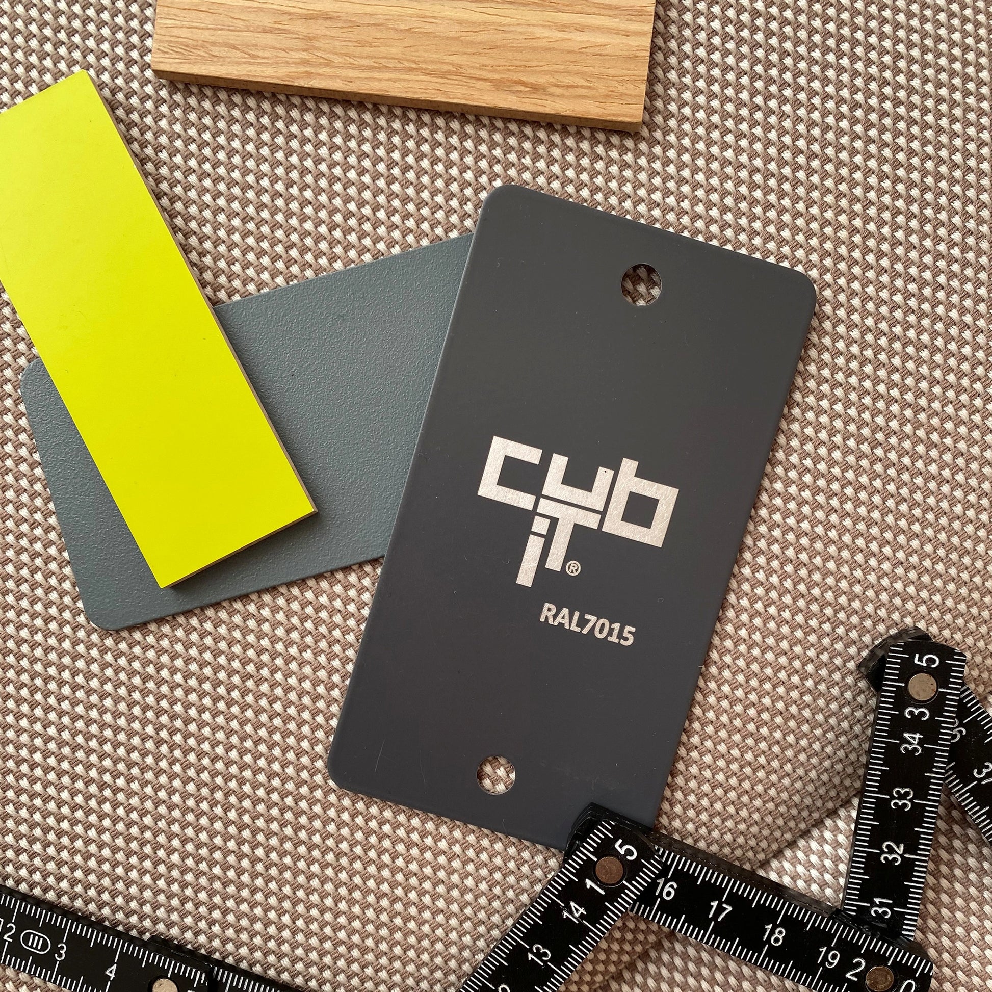 Material samples in wood, yellow and grey tones (RAL7015) on a fabric background with a ruler – for customer consultation